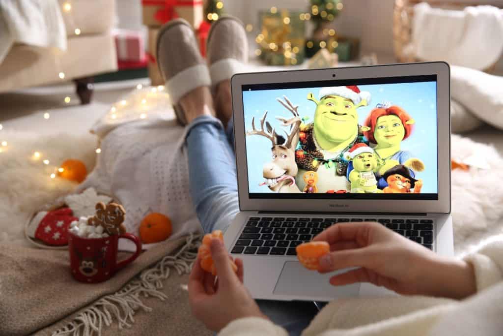 Photo of someone watching Shrek on their laptop while lying on their bed and holding mandarins.